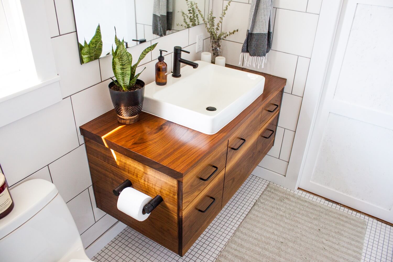Steps to remodel a bathroom - modern decorated bathroom vanity in a modern white bathroom with natural light and plants.